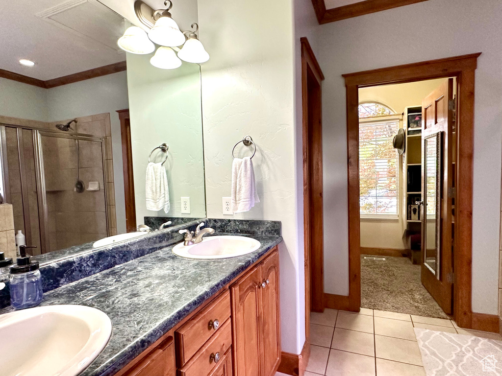 Full bathroom featuring ornamental molding, a stall shower, double vanity, tile patterned floors, and baseboards