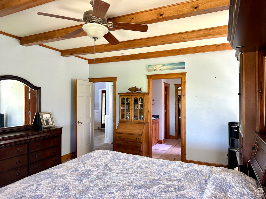 Tiled bedroom featuring beamed ceiling, baseboards, and ceiling fan
