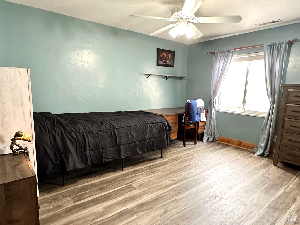 Bedroom featuring light wood-type flooring, a ceiling fan, and baseboards