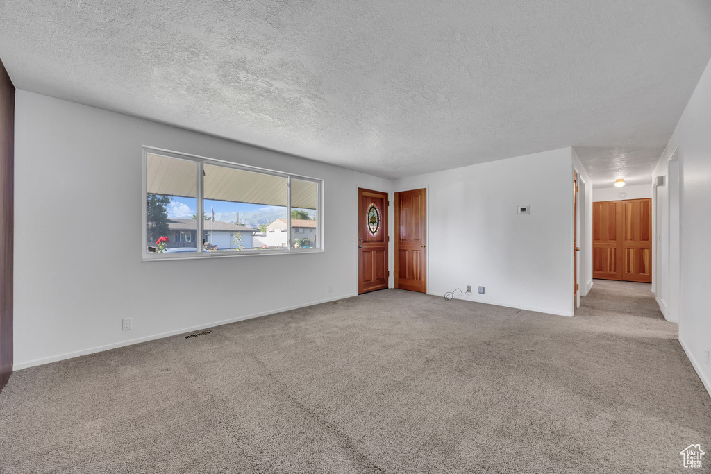 Carpeted spare room featuring a textured ceiling