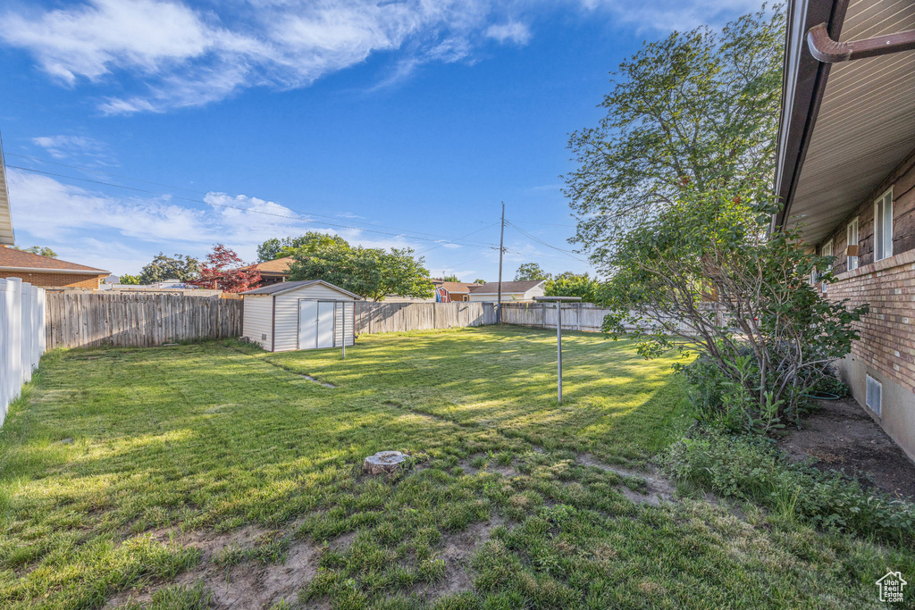 Fenced backyard featuring a shed