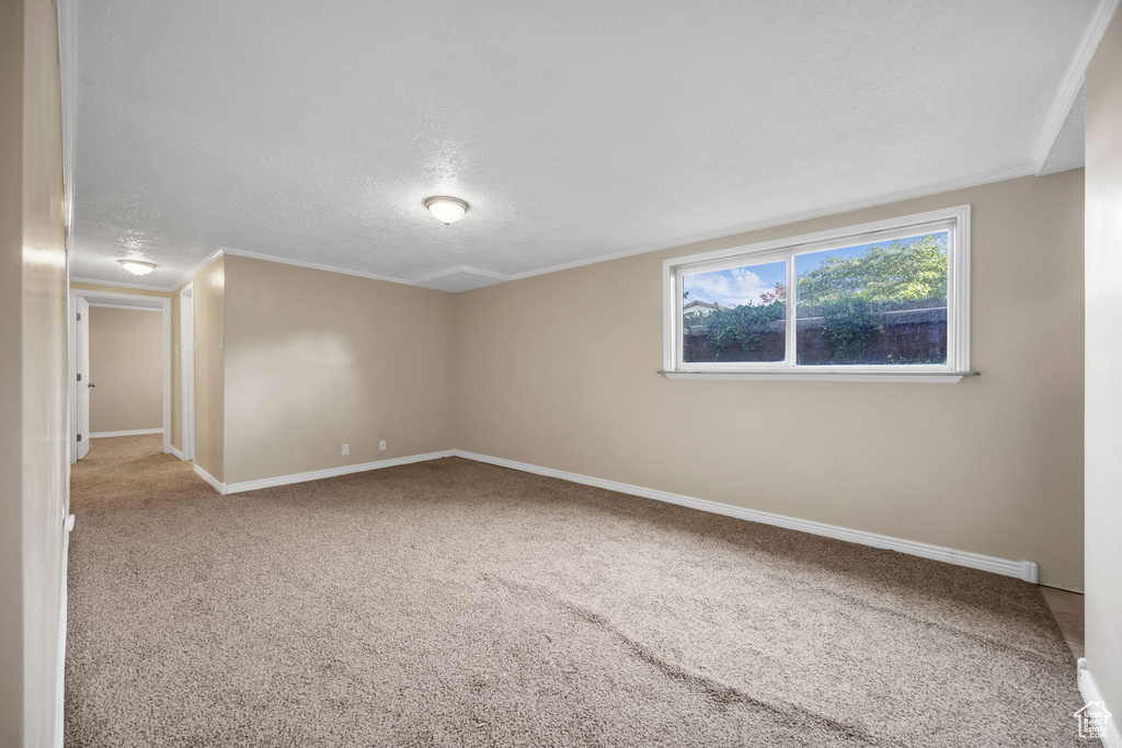 Carpeted empty room with a textured ceiling and baseboards