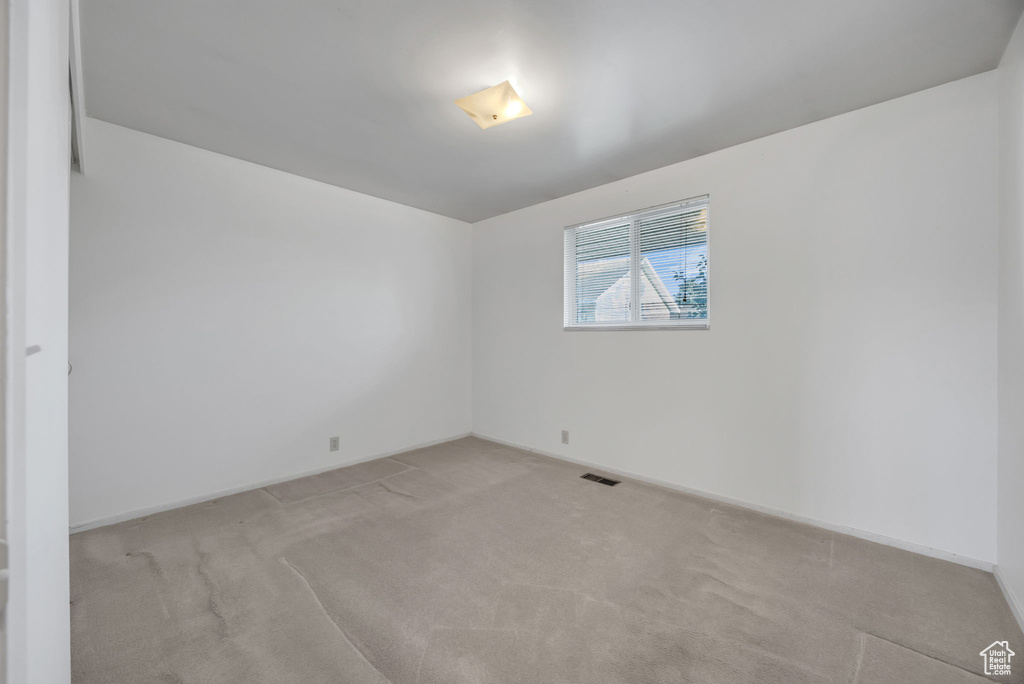 Empty room featuring light colored carpet and baseboards