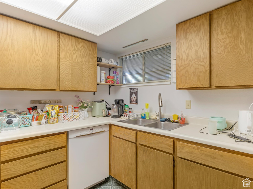 Kitchen with white dishwasher, a sink, light countertops, and open shelves
