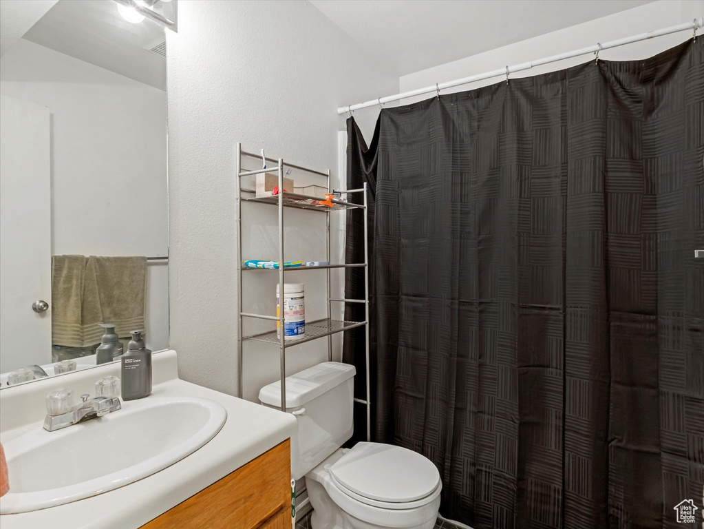 Full bathroom with vanity, toilet, and curtained shower