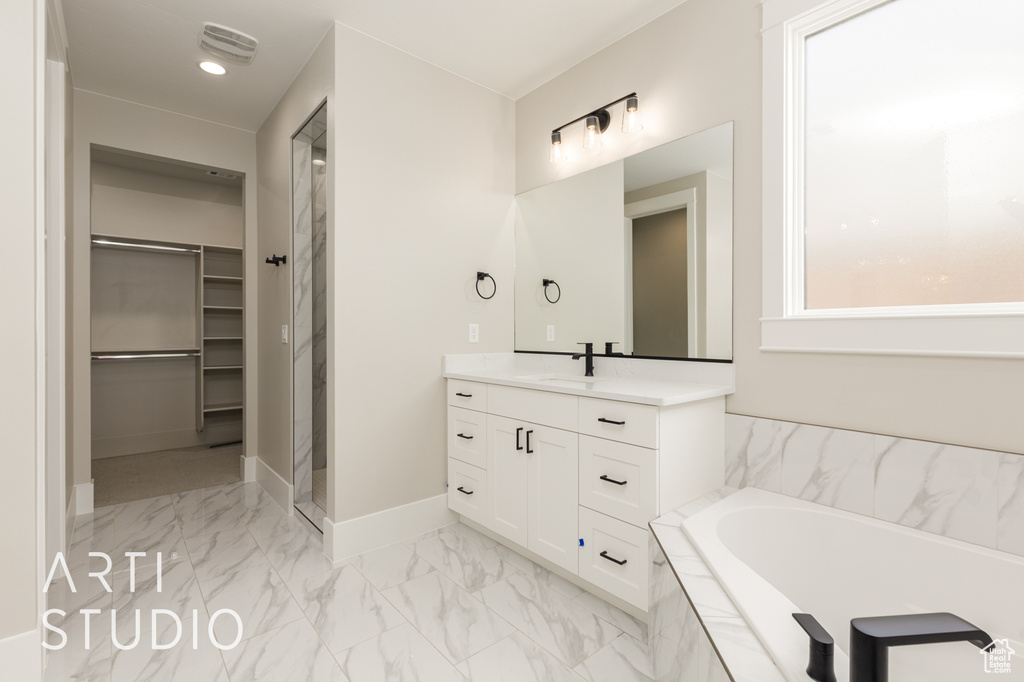 Bathroom featuring a spacious closet, vanity, marble finish flooring, a bath, and a stall shower