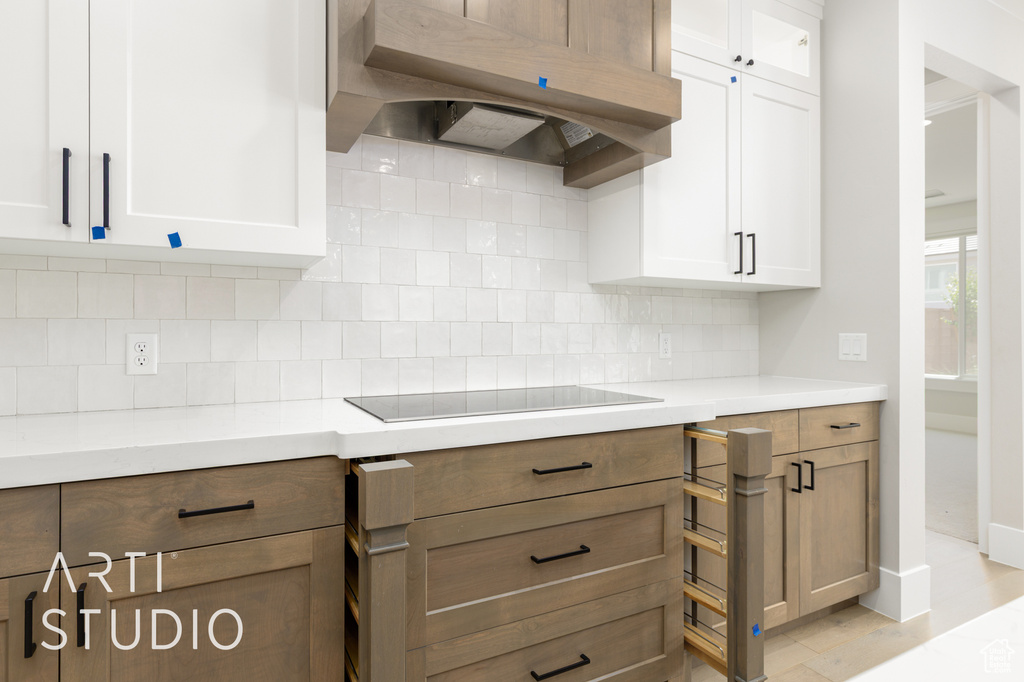 Kitchen with range hood, white cabinetry, and light countertops