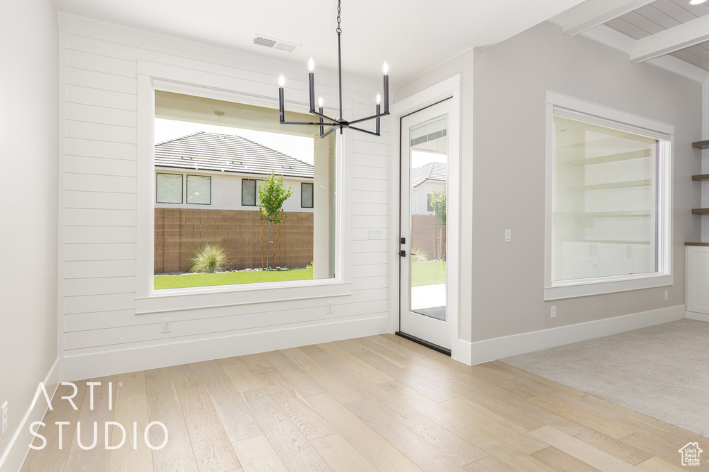 Unfurnished dining area featuring a chandelier, wood finished floors, and baseboards
