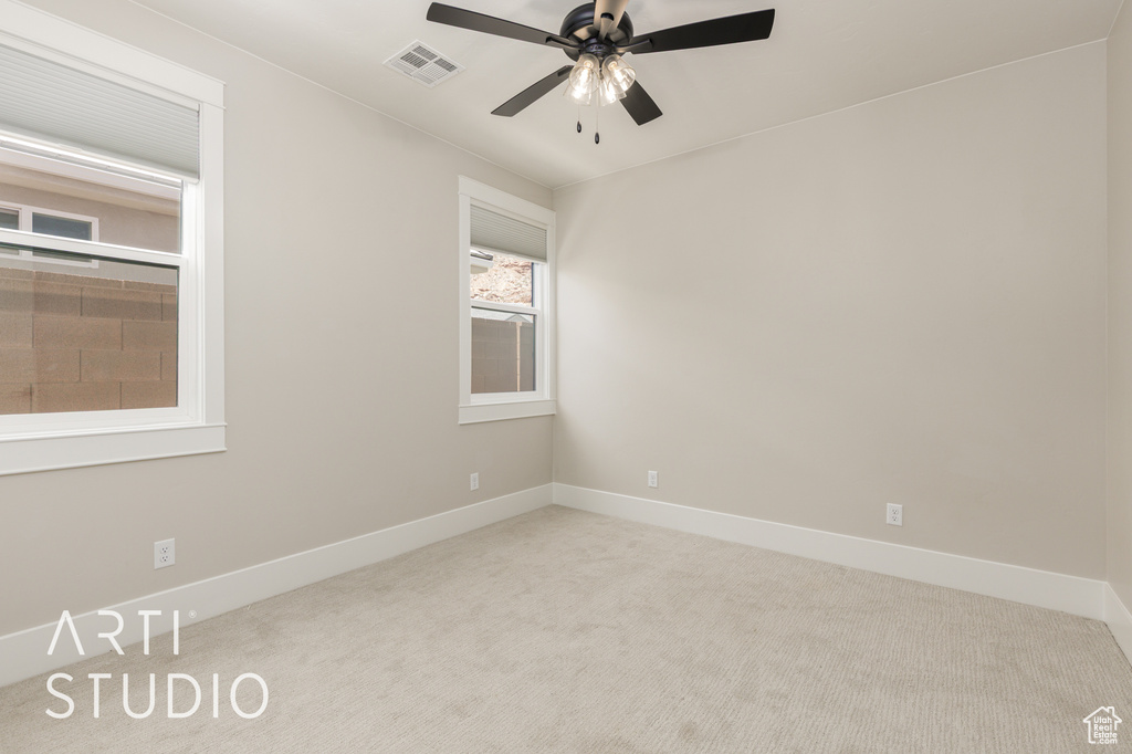 Carpeted spare room featuring ceiling fan and baseboards