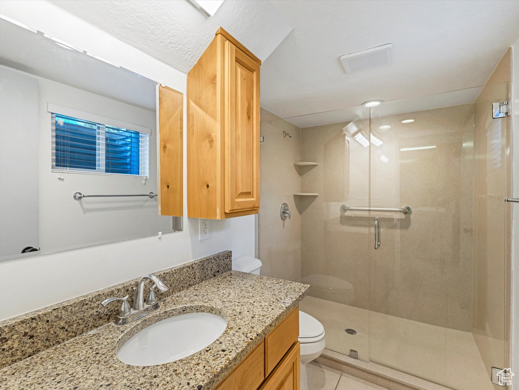 Full bathroom featuring a shower stall, vanity, and tile patterned flooring