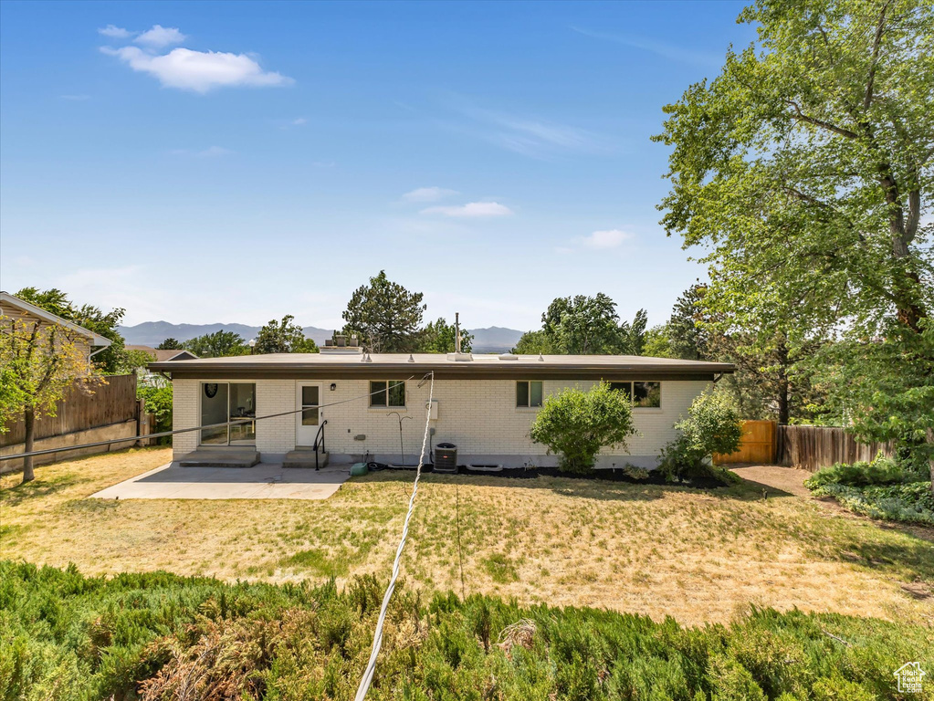 Rear view of property with a patio, brick siding, a mountain view, and a fenced backyard
