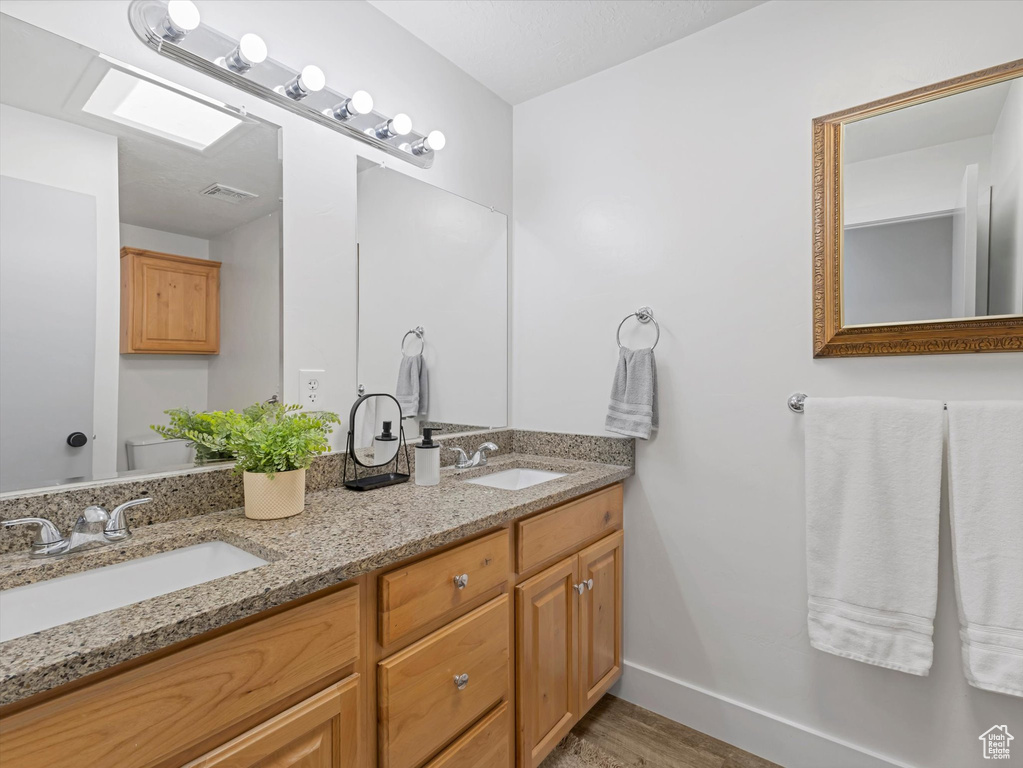 Full bathroom with double vanity and wood finished floors