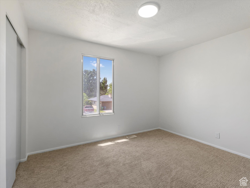 Carpeted spare room with baseboards and a textured ceiling