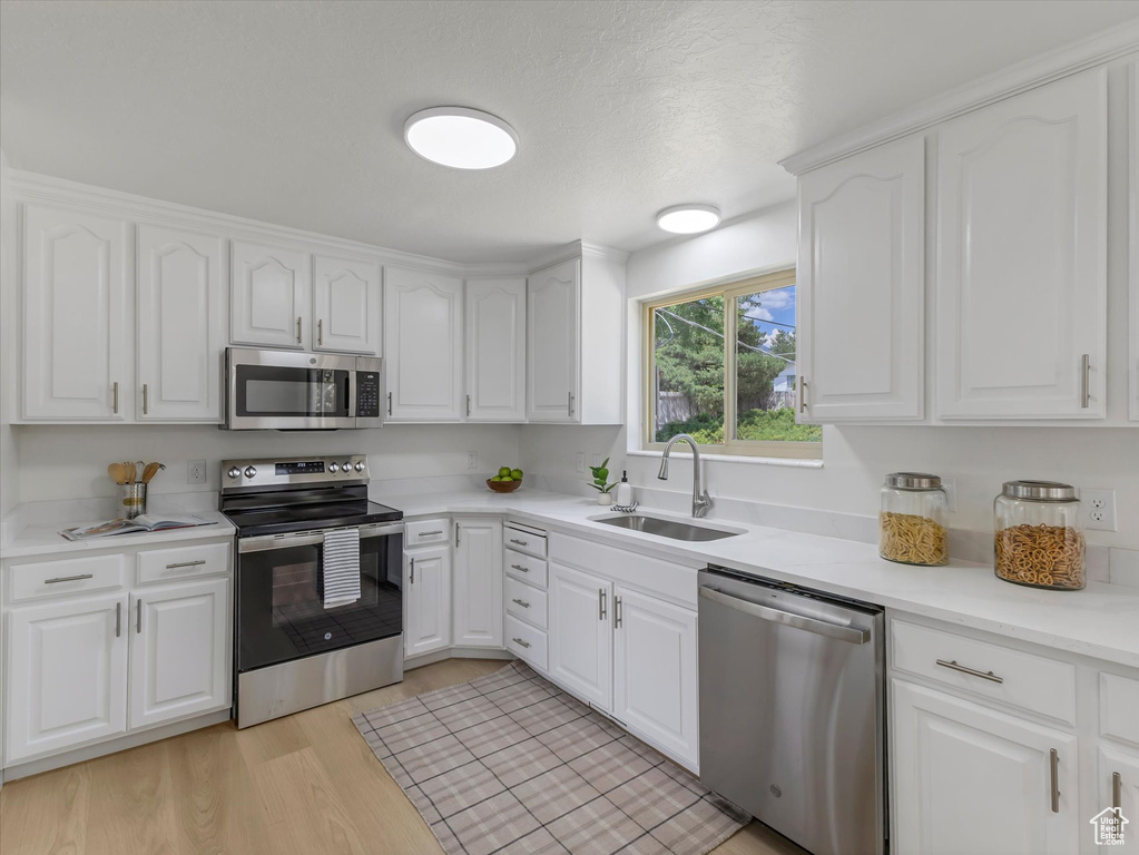 Kitchen featuring stainless steel appliances, white cabinetry, and light wood finished floors