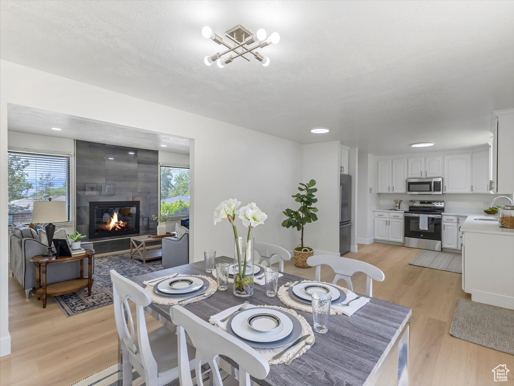 Dining area featuring healthy amount of natural light, light wood-style floors, and a fireplace