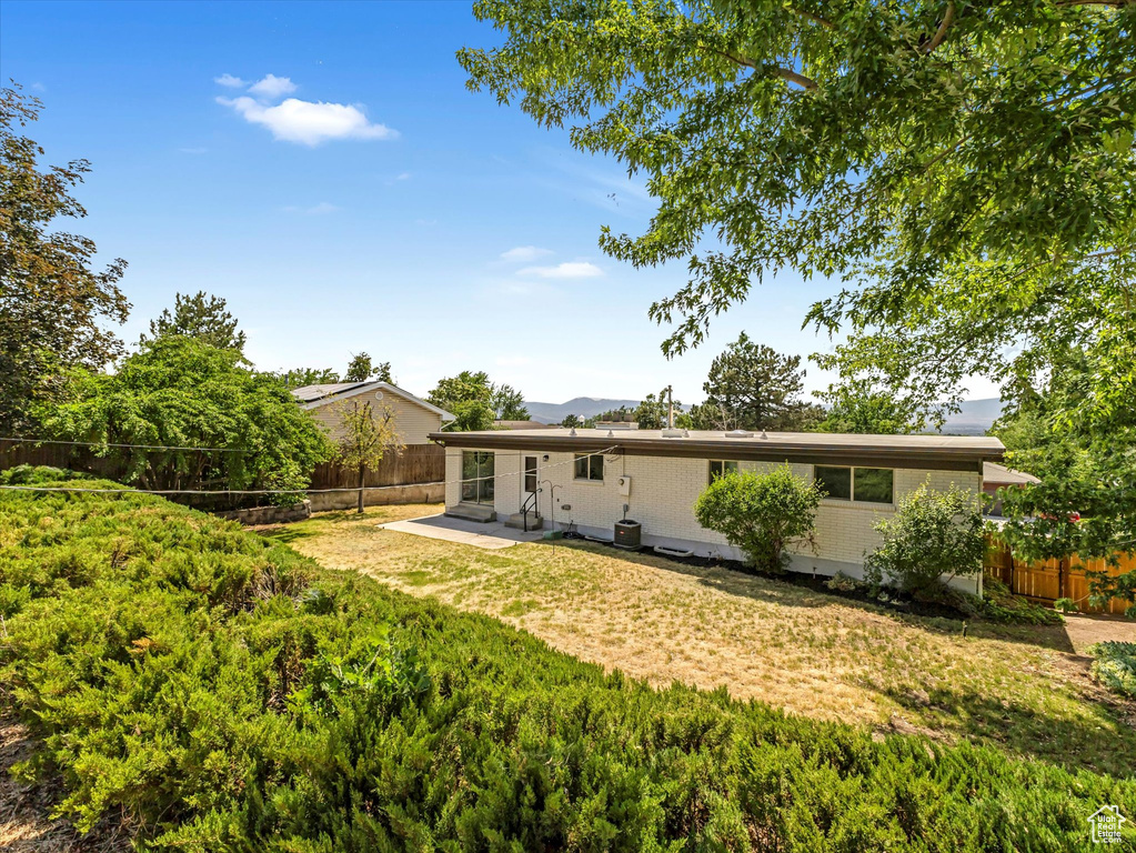 Rear view of house featuring a fenced backyard, brick siding, a patio, and entry steps