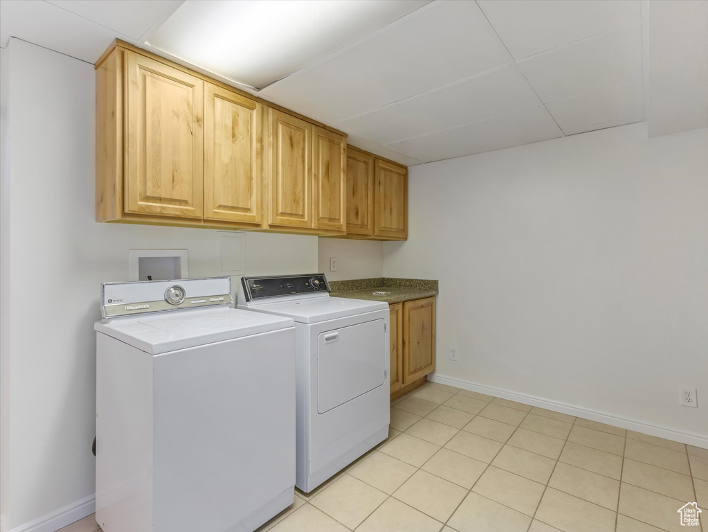 Laundry room featuring cabinet space, independent washer and dryer, and light tile patterned floors