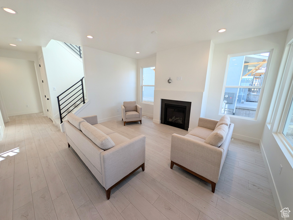 Living area featuring stairway, a fireplace, light wood finished floors, and recessed lighting