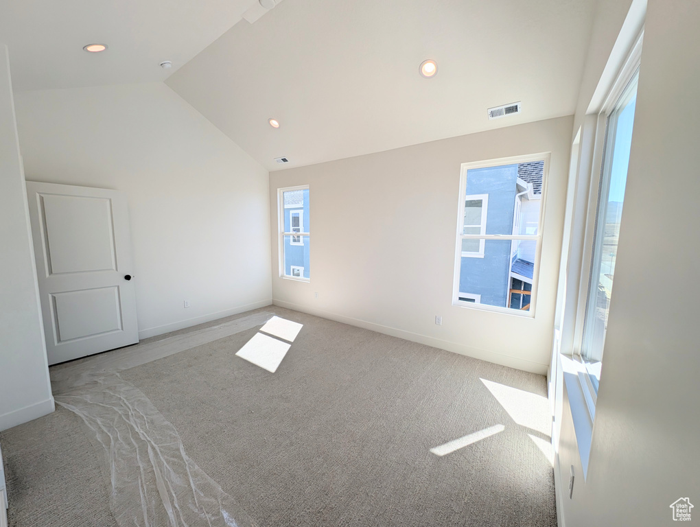 Empty room featuring carpet floors, vaulted ceiling, plenty of natural light, and recessed lighting