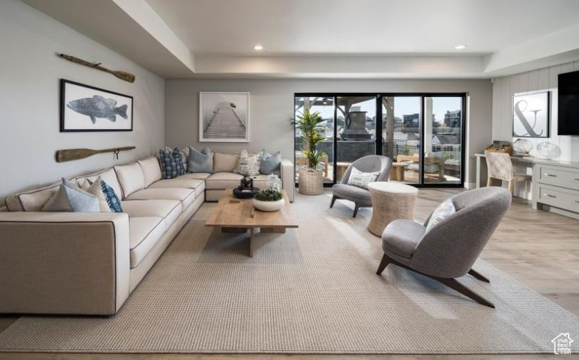 Living area with a raised ceiling, wood finished floors, and recessed lighting