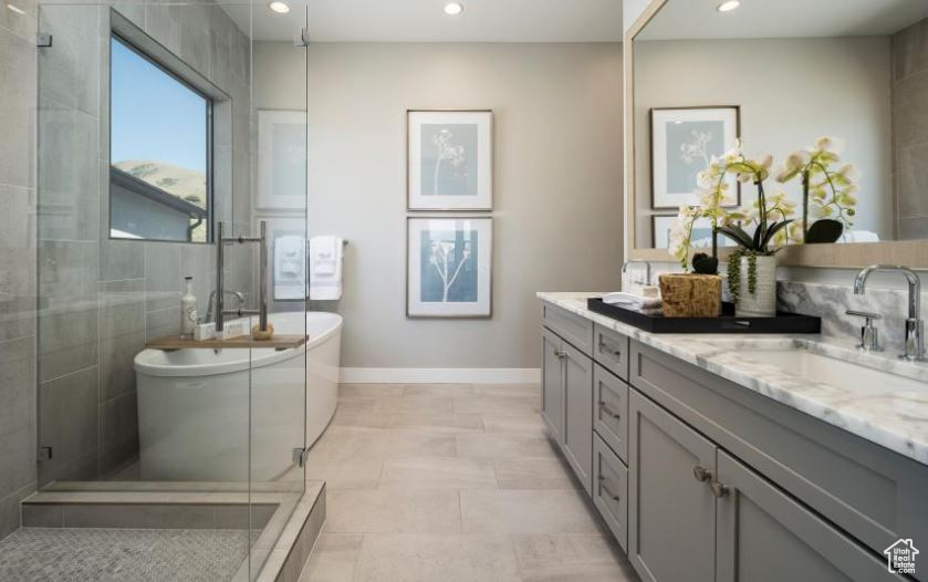 Bathroom with double vanity, a freestanding tub, recessed lighting, and tiled shower