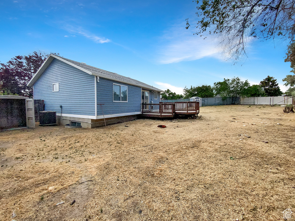 Back of property with a wooden deck and roof with shingles