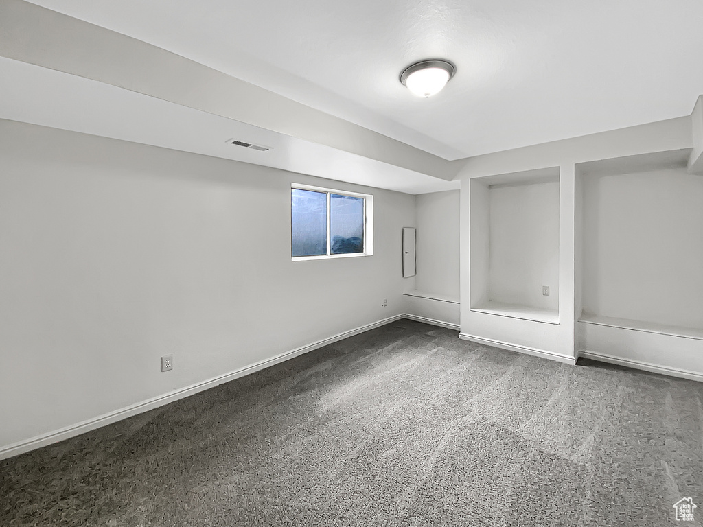 Basement featuring dark colored carpet and baseboards