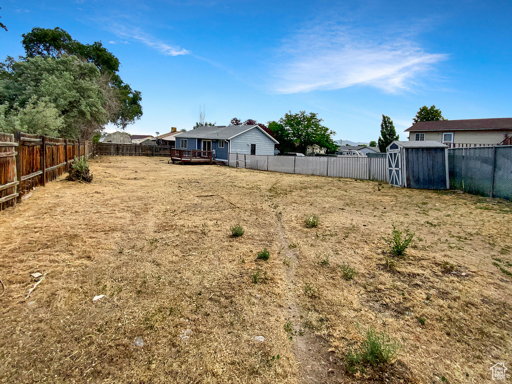Fenced backyard with a shed and a wooden deck