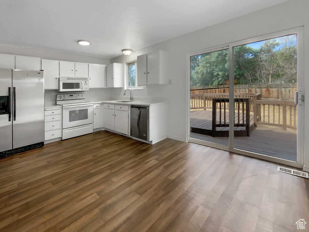 Kitchen featuring stainless steel appliances, light countertops, dark wood finished floors, and white cabinetry