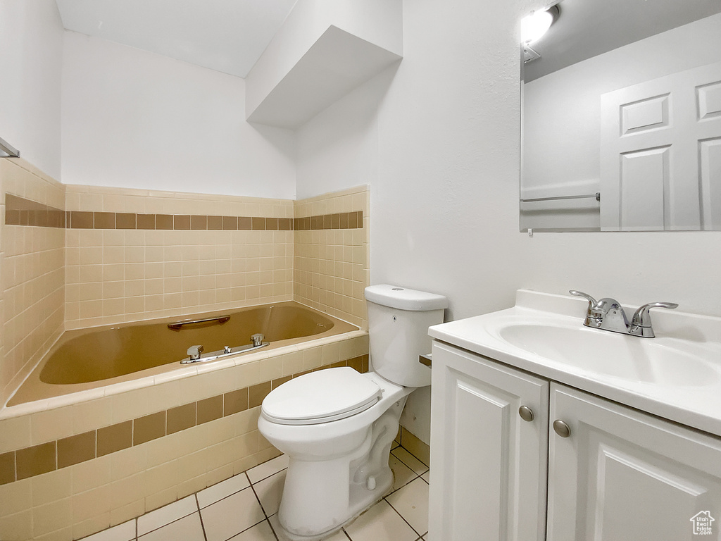 Full bathroom with a relaxing tiled tub, vanity, and tile patterned floors