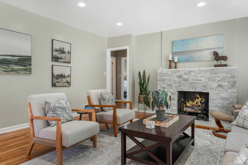 Living room featuring a stone fireplace, wood finished floors, and recessed lighting