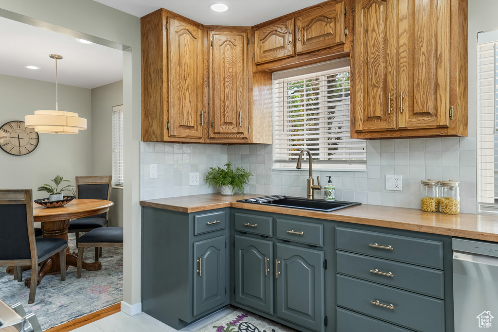 Kitchen featuring light countertops, stainless steel dishwasher, backsplash, and recessed lighting