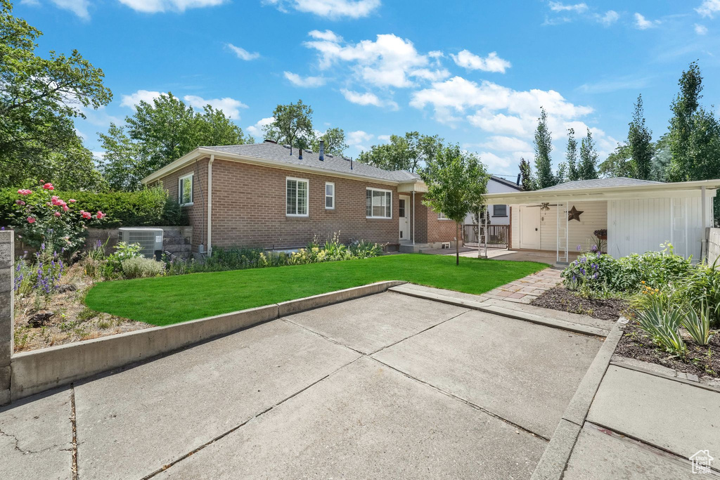 Back of house featuring brick siding, a lawn, and a patio