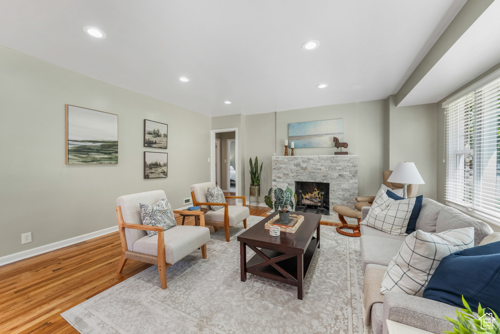 Living area featuring wood finished floors, recessed lighting, and a stone fireplace