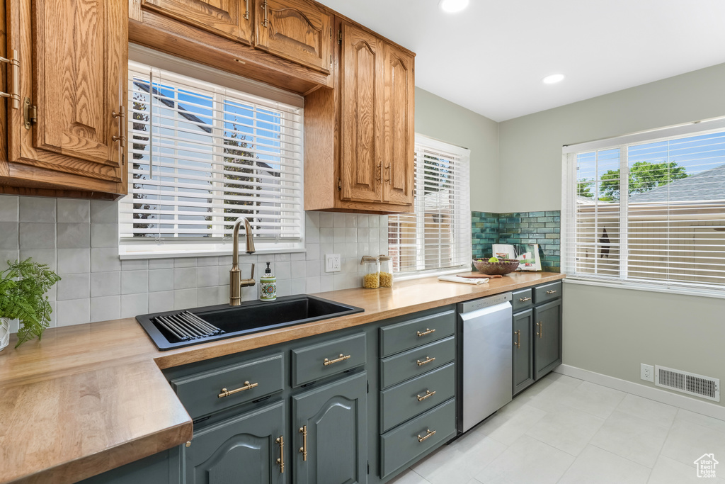 Kitchen featuring stainless steel dishwasher, decorative backsplash, light countertops, recessed lighting, and light tile patterned floors