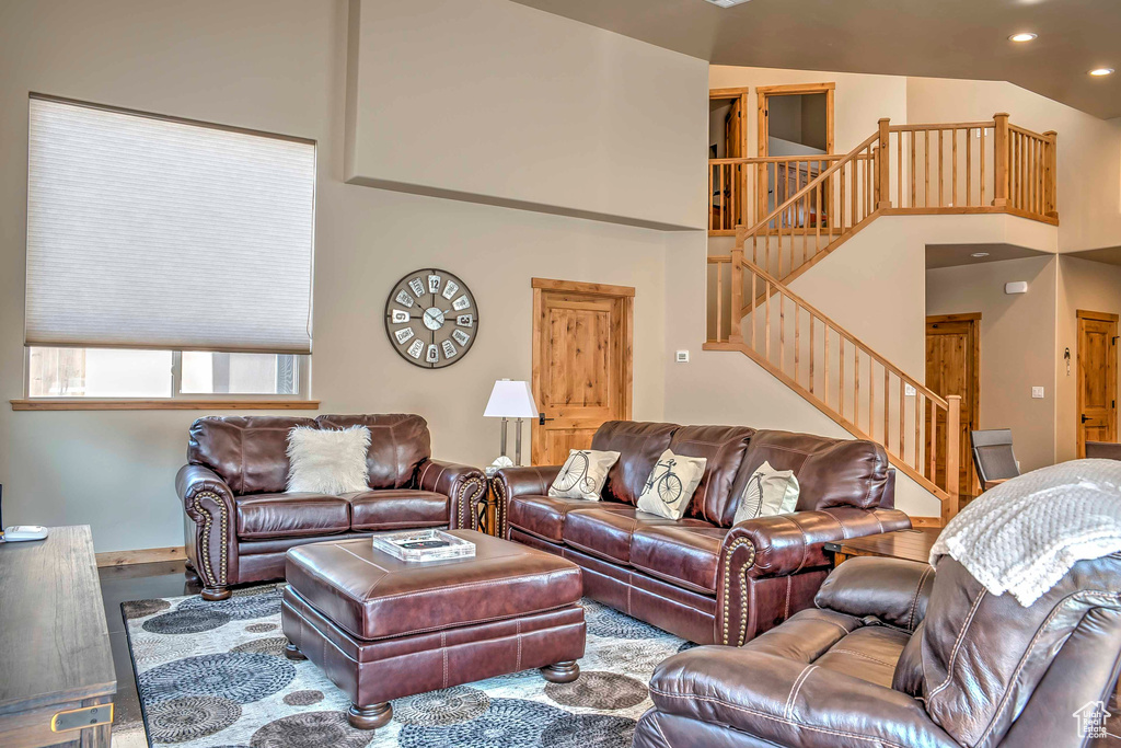 Living room with stairway, recessed lighting, and high vaulted ceiling