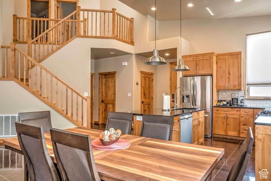 Dining room featuring stairway, recessed lighting, dark tile patterned floors, and a high ceiling