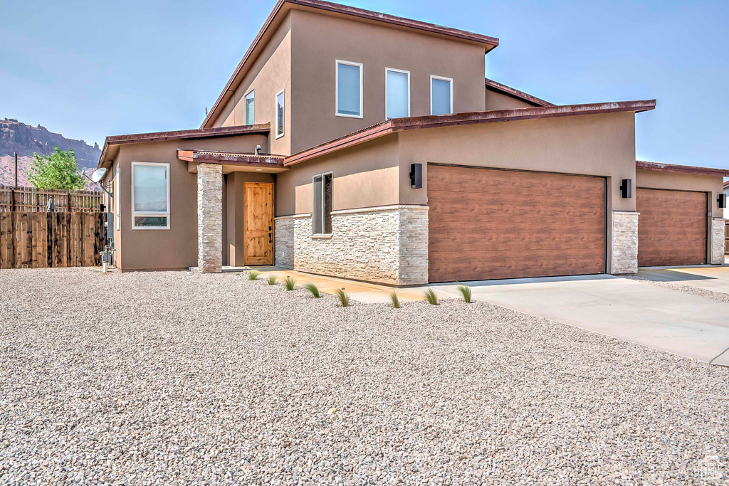 View of front of property featuring stone siding, stucco siding, driveway, a mountain view, and an attached garage