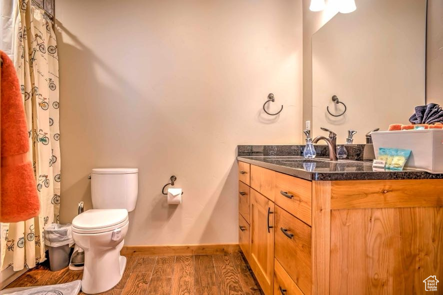 Full bath with wood finished floors, vanity, toilet, and baseboards
