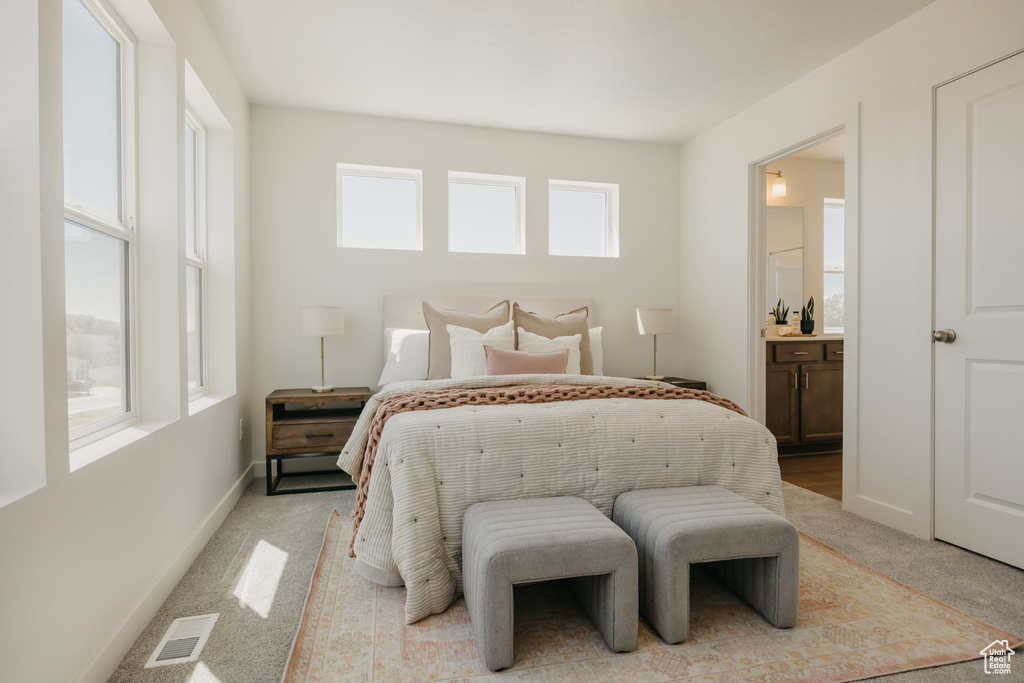 Bedroom featuring light colored carpet and ensuite bathroom