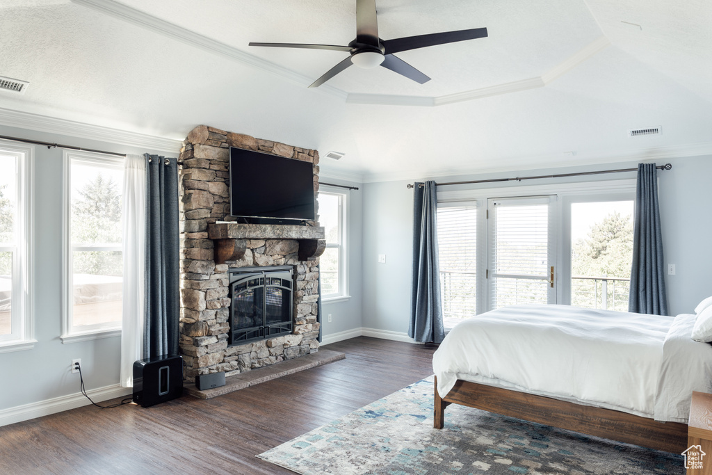 Bedroom with access to exterior, crown molding, a stone fireplace, wood finished floors, and ceiling fan