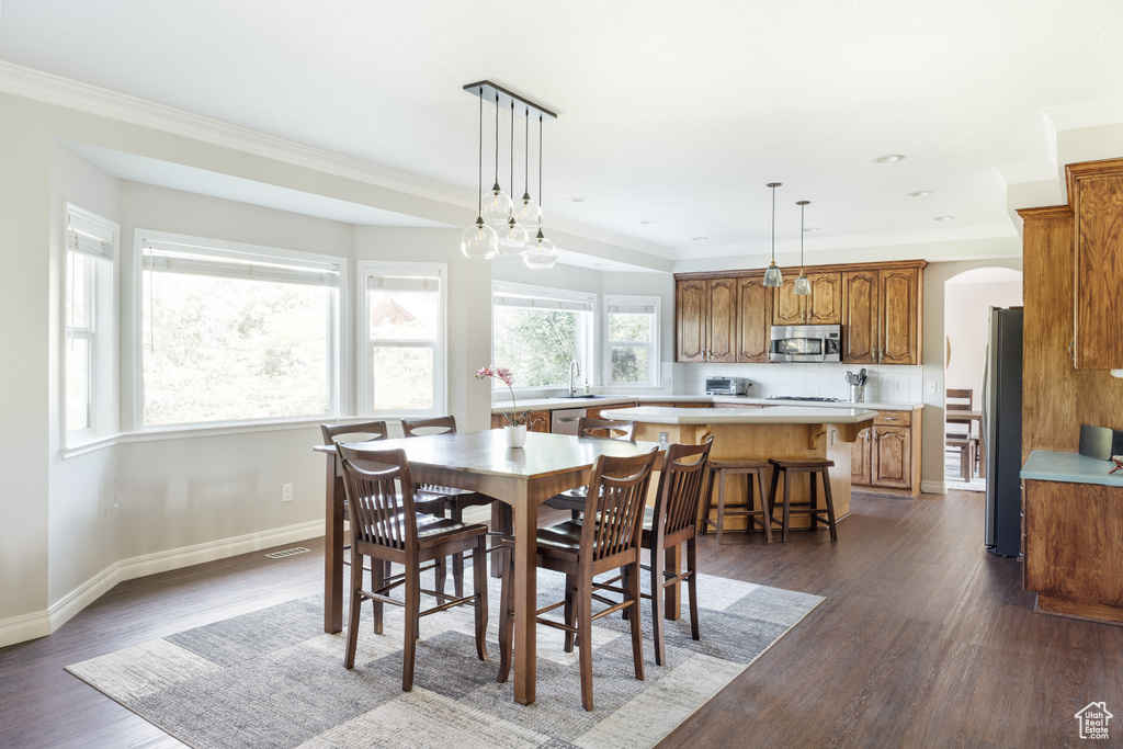 Dining room featuring dark wood-style floors, arched walkways, and ornamental molding