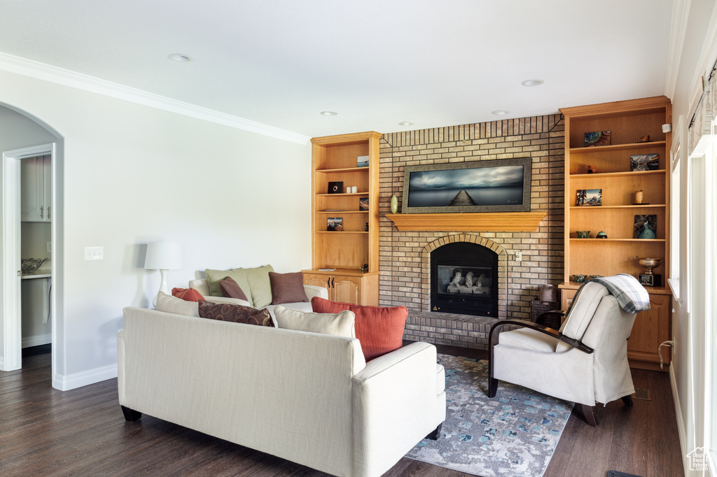 Living area with crown molding, a fireplace, arched walkways, dark wood-type flooring, and recessed lighting