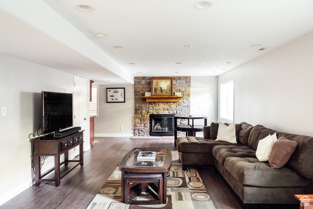Living area with a stone fireplace, dark wood-style floors, and recessed lighting