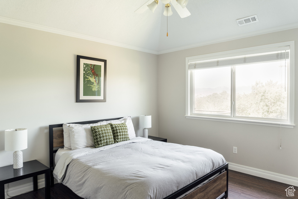 Bedroom featuring dark wood-style floors, ornamental molding, and ceiling fan