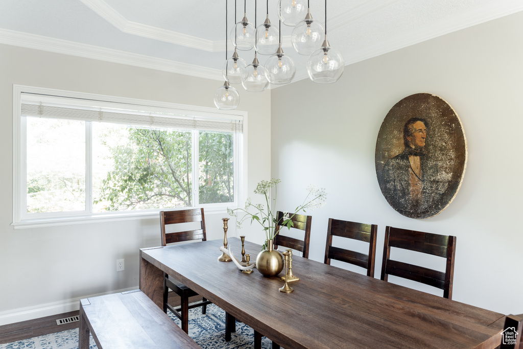 Dining space with wood finished floors and crown molding