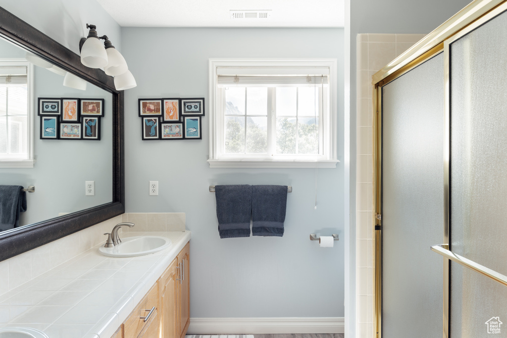 Full bathroom featuring double vanity and an enclosed shower