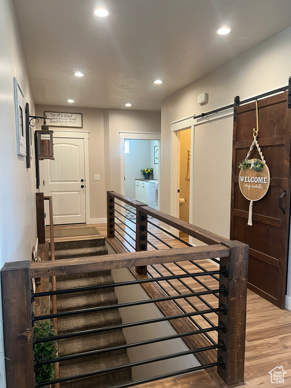 Staircase featuring recessed lighting, wood finished floors, and a barn door