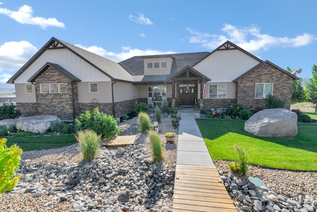 Craftsman-style home featuring stone siding and a front lawn