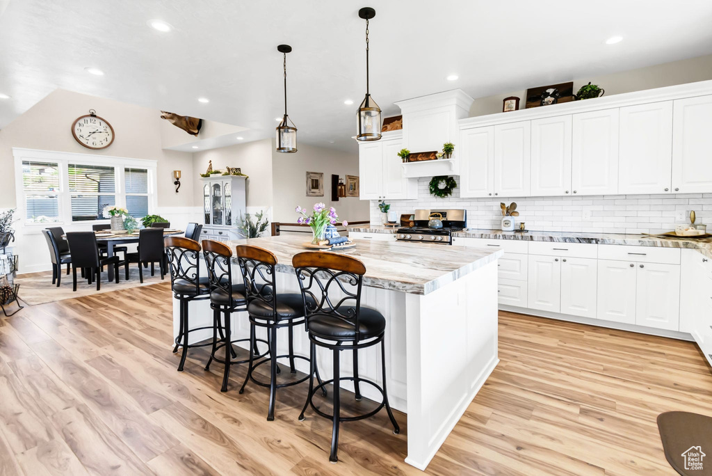 Kitchen featuring stainless steel gas range oven, a kitchen island, light wood-type flooring, white cabinets, and recessed lighting